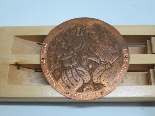 The engravings on Purim Grogger pine wood are handmade & hammered copper silver plated showing queen Esther at the dinner she invited the king.