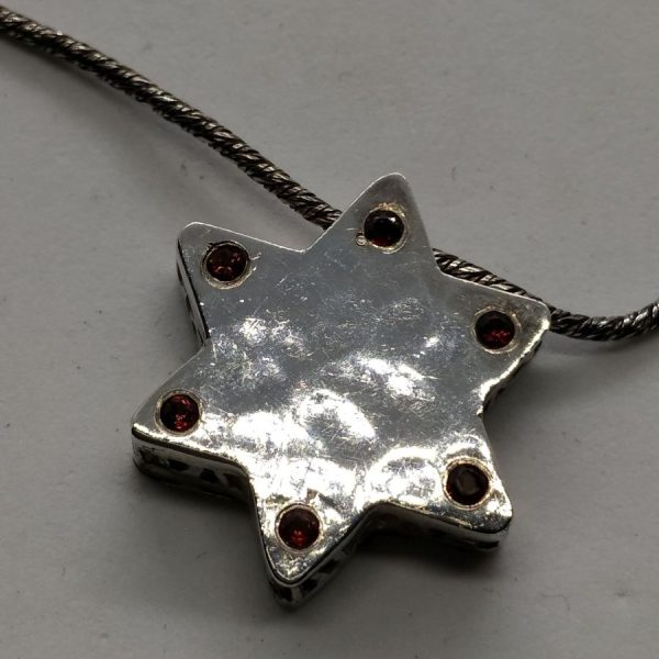 Handmade contemporary sterling silver and 14 carat gold MagenDavid Star Hammered Gold hammered set with Garnets on one side of star.