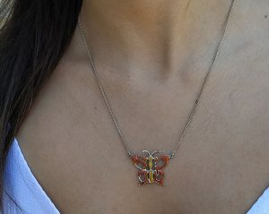 A handmade original design sterling silver necklace Mazal Tov made out of the Hebrew words Mazal Tov Good luck in Hebrew enameled with orange colors.